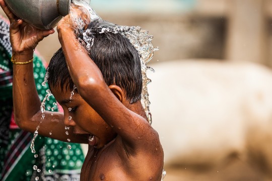 young boy pouring water on his head