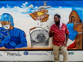 Haitian man standing in front of a painted mural
