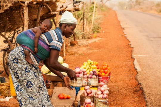 Mère et enfant qui vendent des fruits sur le bord de la route