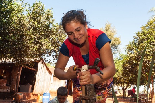 Woman adjusting a water faucet in Paraguay
