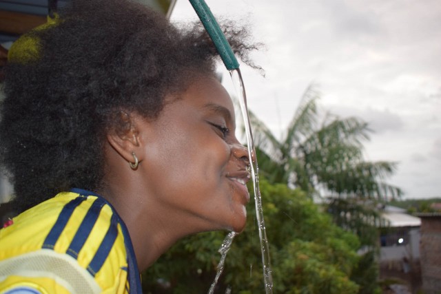 woman drinking water from a hose