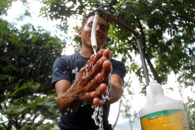 man washing his hands under water