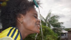 woman drinking water from a hose